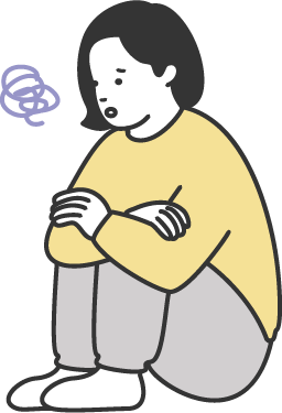 膝を抱えて悩んでいる女性