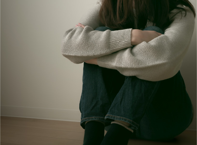 落ち込んで膝を抱えている女性